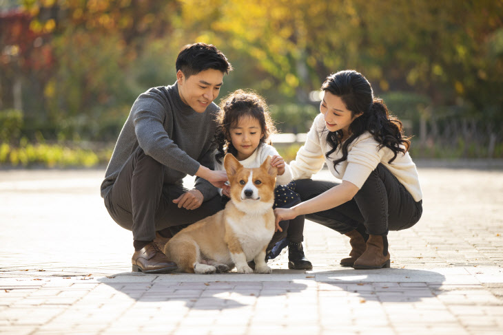 Happy young family and pet dog in park